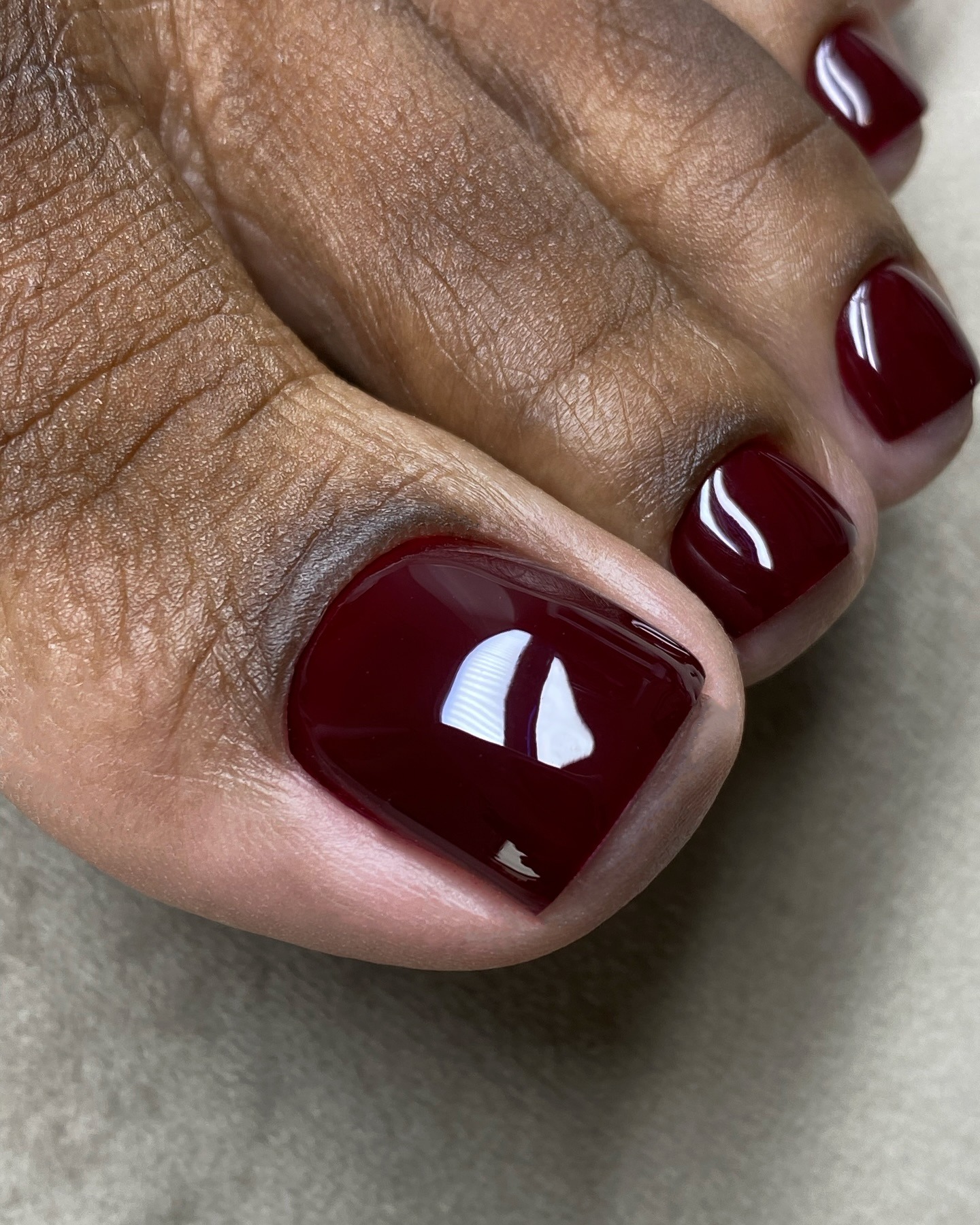 A close-up picture of a glossy burgundy pedicure