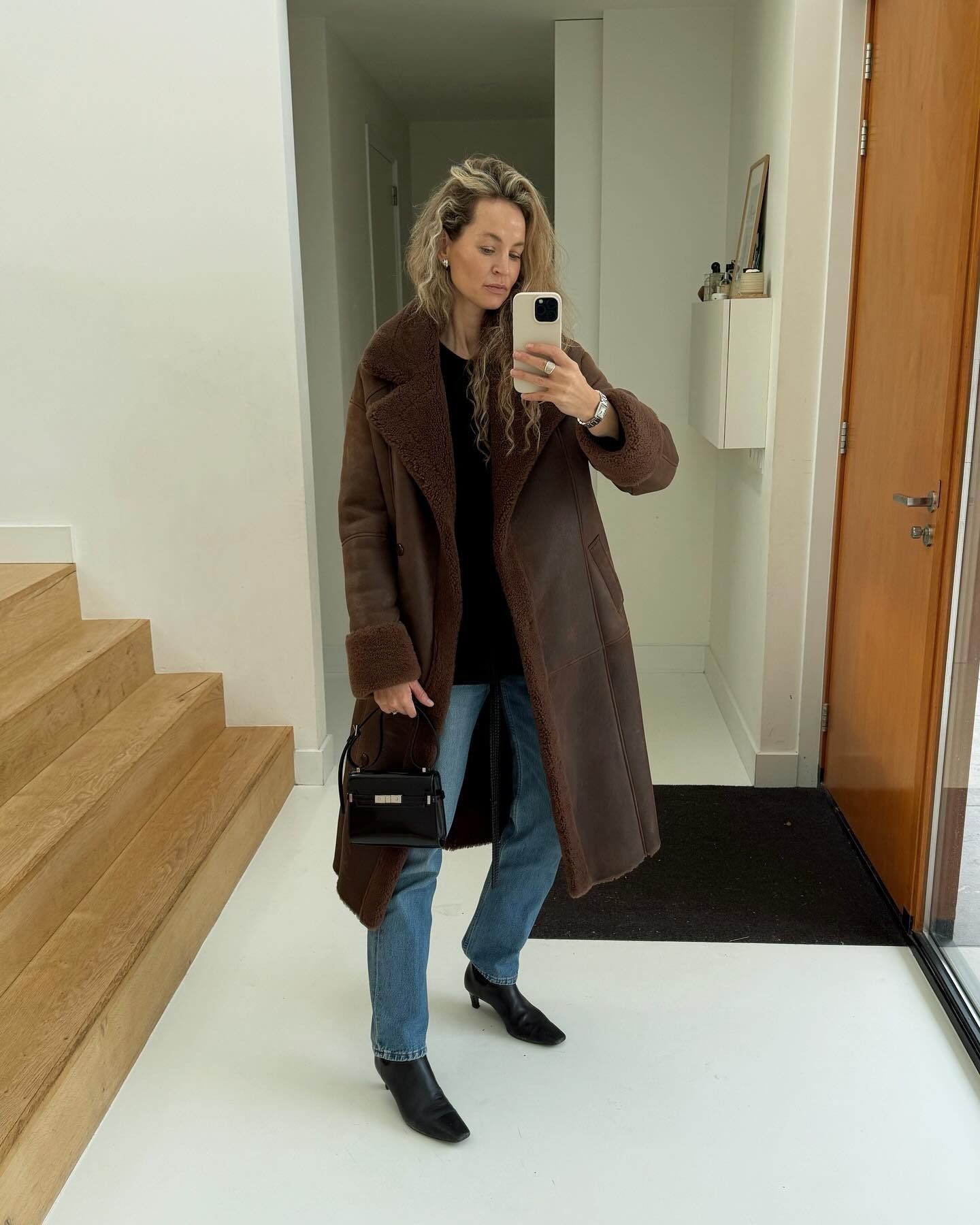 An influencer wears a long coat with jeans and heeled sock boots.