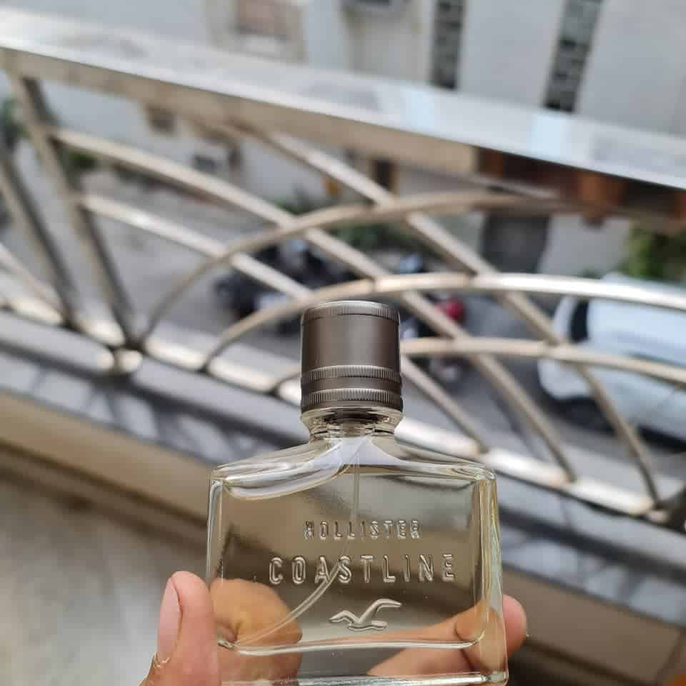 holding a bottle of hollister coastline cologne